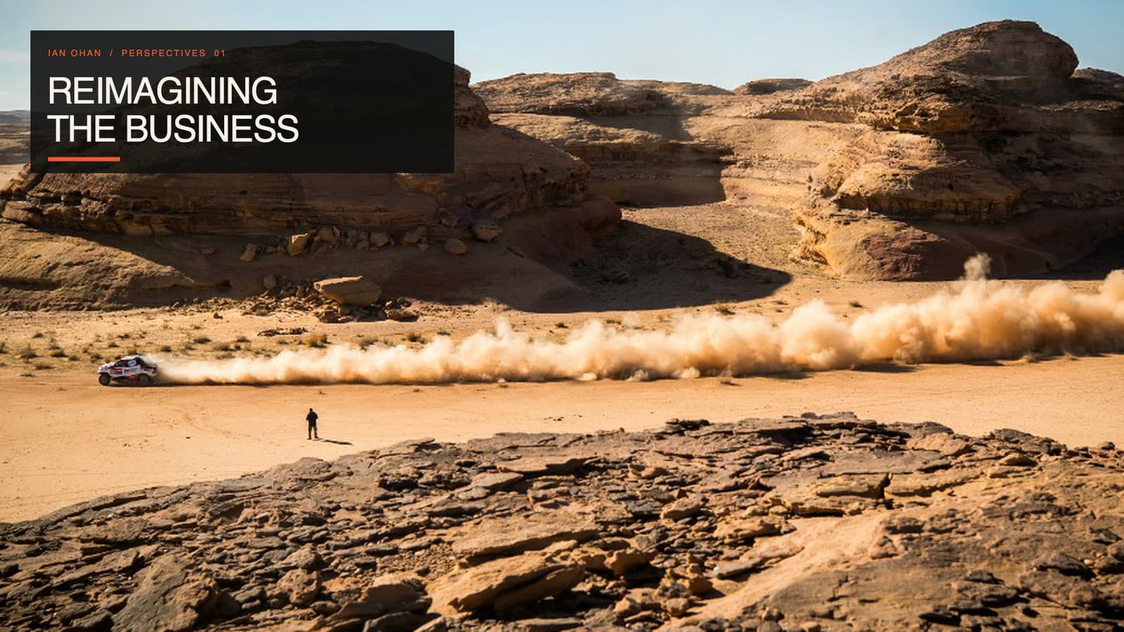 A lone observer watches a Dakar rally car accelerate across the Saudi desert, leaving a long dust trail beneath the title “Reimagining the Business.”
